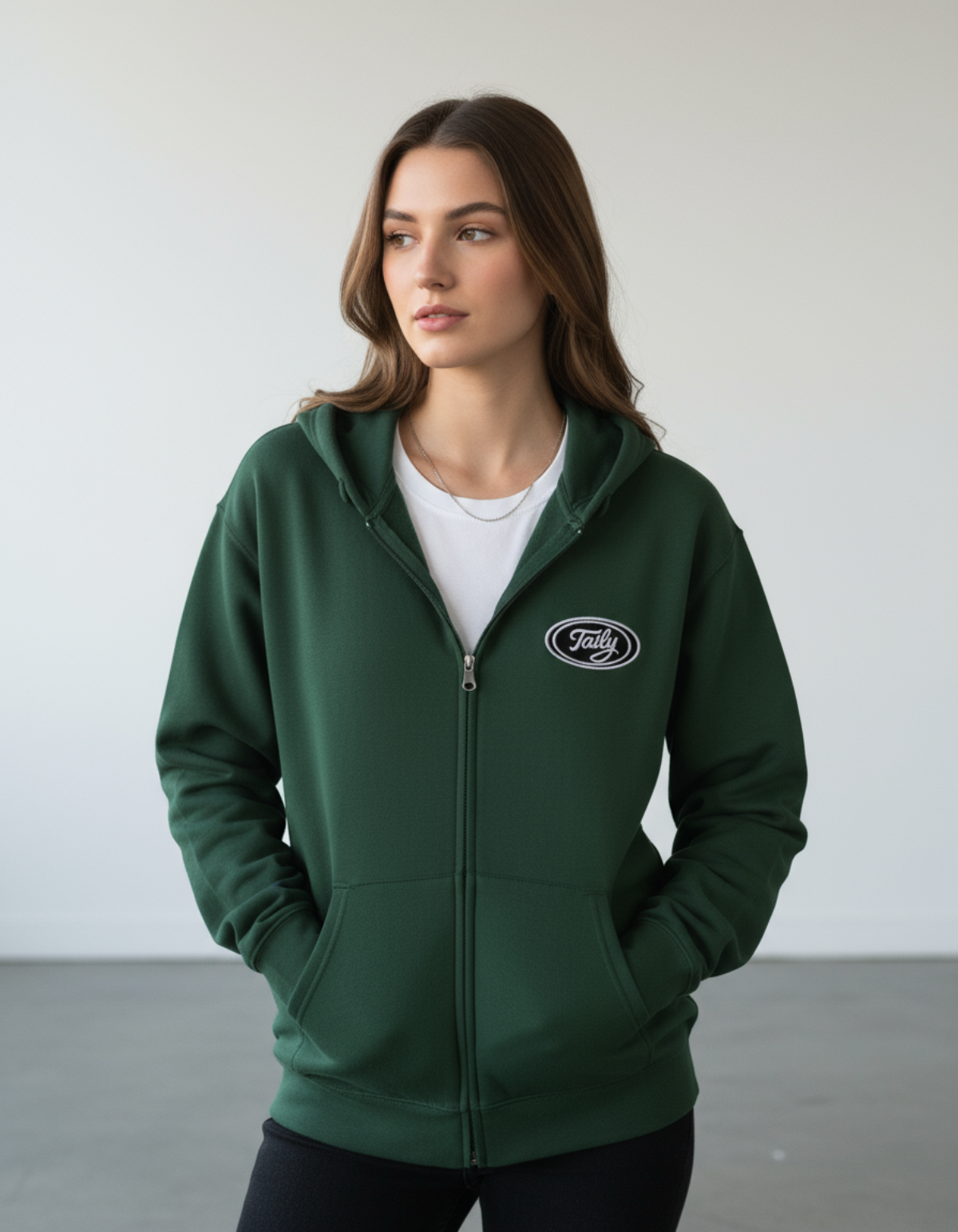 Taily Zip Hoodie in forest green, showcasing embroidered logo and relaxed fit on model.