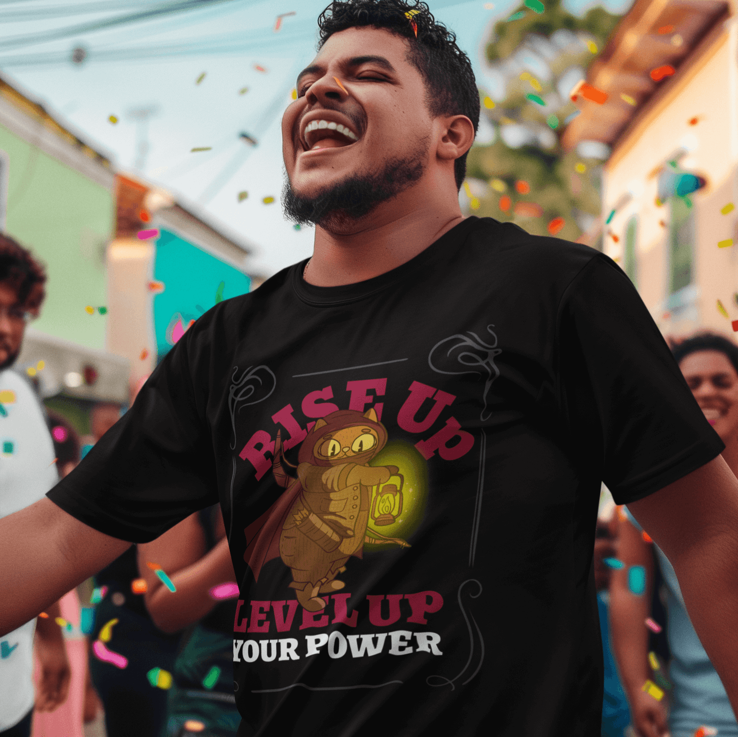 Happy man wearing a black T-shirt with a warrior cat holding a glowing lantern design and the text 'RISE UP, LEVEL UP YOUR POWER,' celebrating outdoors with colorful confetti in the background.