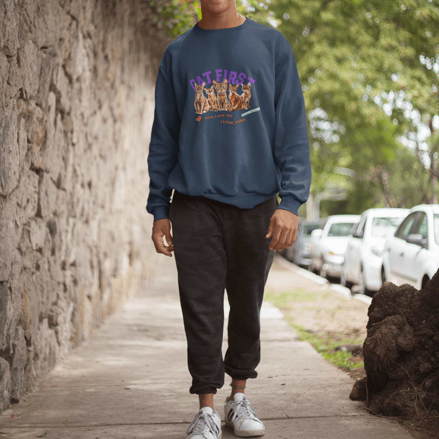 Man wearing a navy sweatshirt featuring Abyssinian cats and the text 