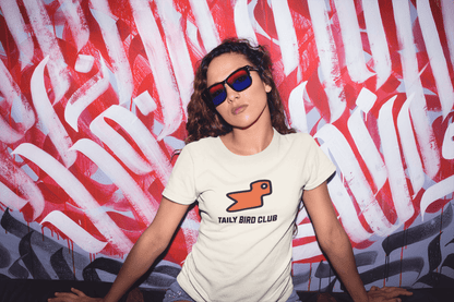 Model wearing Taily Bird Club boxy t-shirt with orange bird design against vibrant graffiti background.