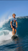 Wave Hounds Surf Tee – White worn by a surfer riding a wave, showcasing the bold retro graphic design.