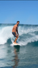 Gorilla Season Surf Tee – Pepper worn by a surfer riding a wave on a sunny beach.