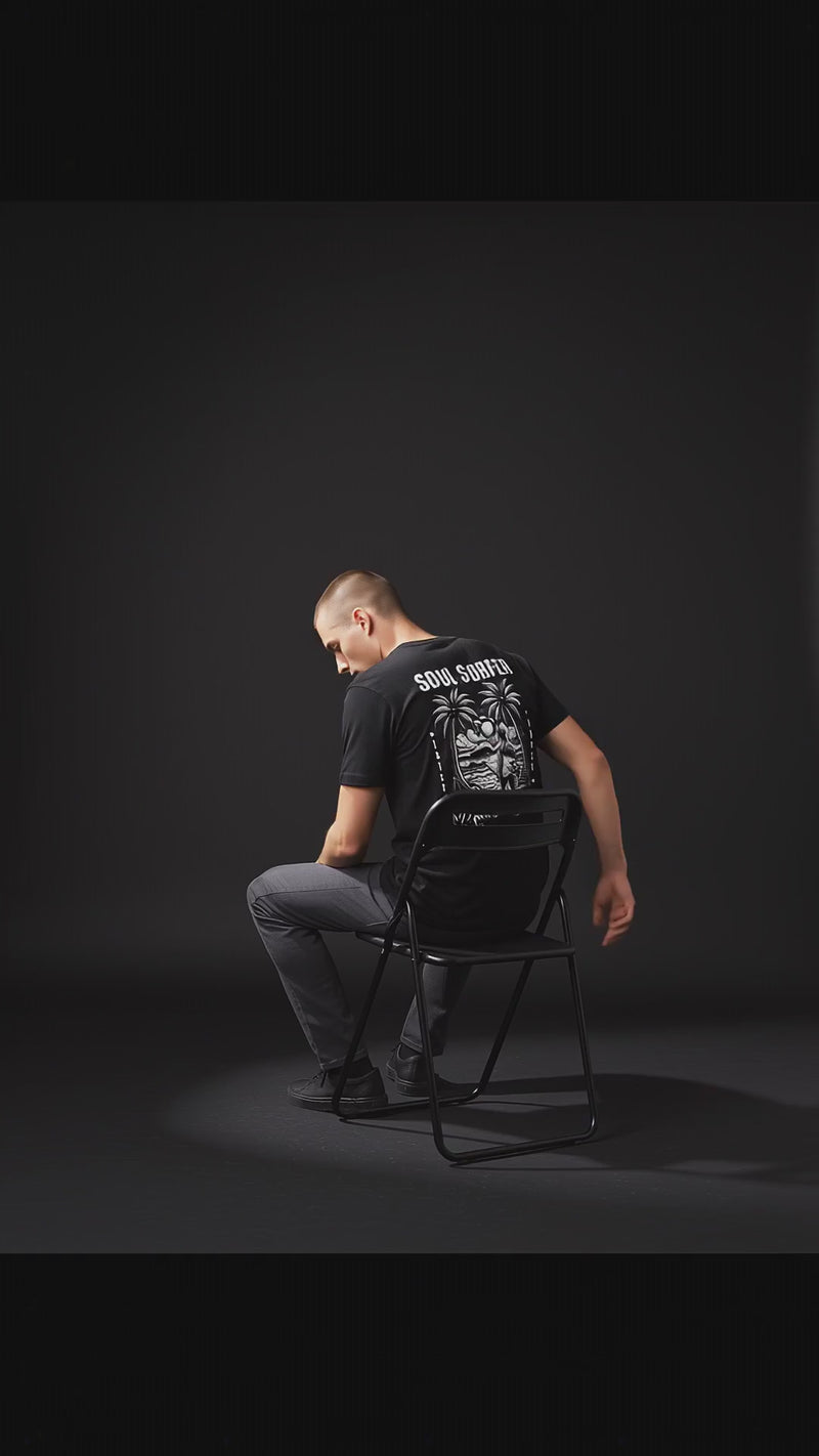 Young man wearing a Soul Surfer Malibu Tee, sitting on a chair, showcasing the back graphic design.