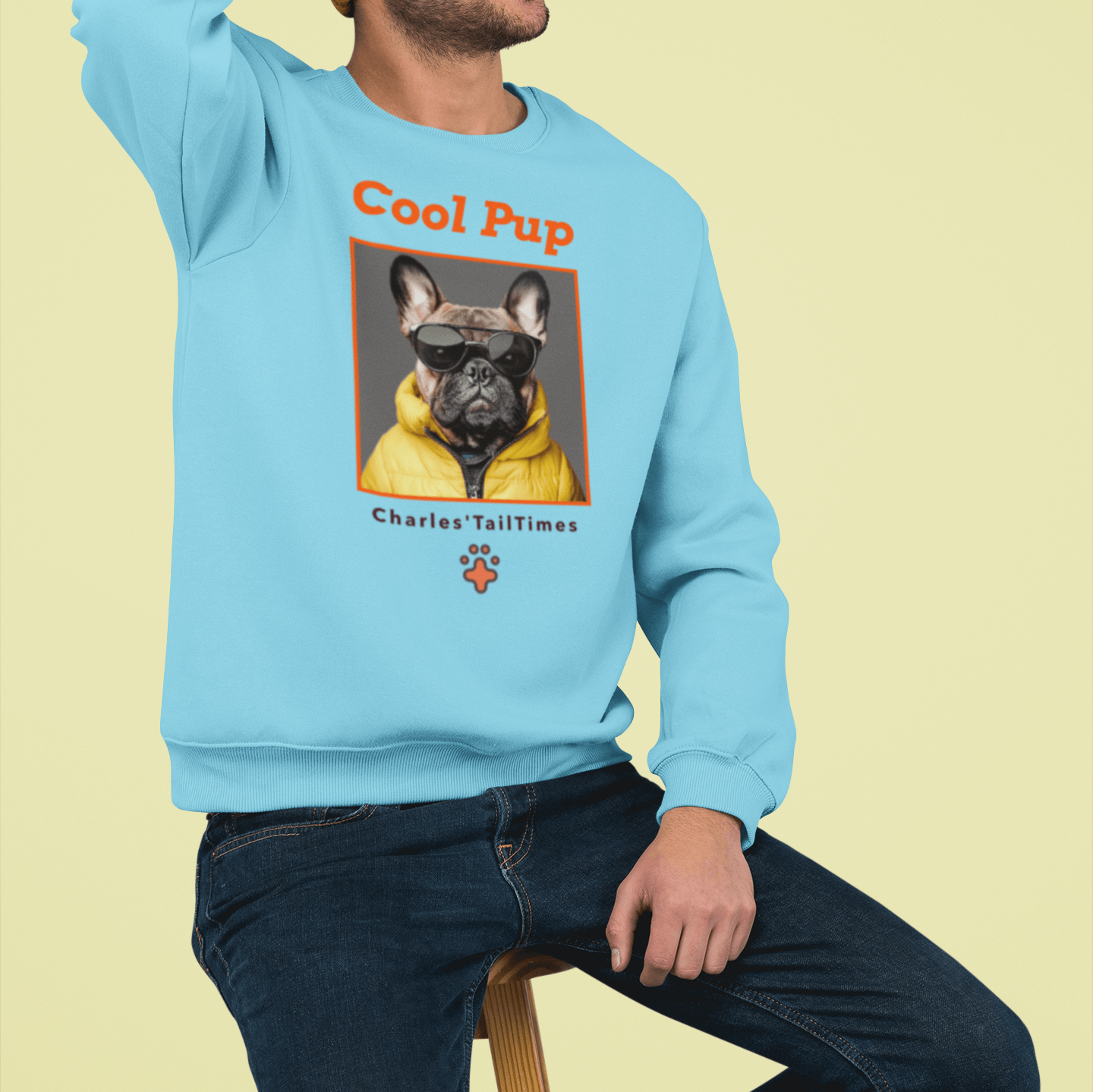 The image shows a young man wearing the "Cool Pup" sweatshirt featuring a French Bulldog in sunglasses and a yellow jacket. The man is wearing a brown knitted hat, and the background is a solid yellow color.