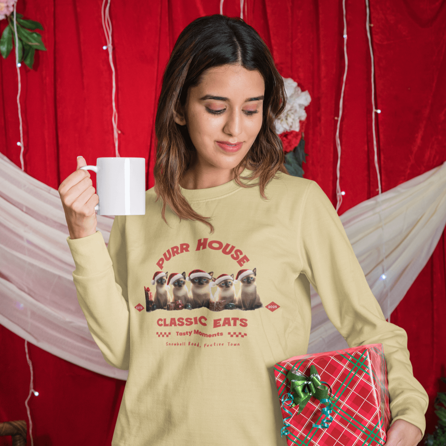 Woman holding a mug in a festive sweatshirt featuring cute Siamese cats, perfect for holiday gatherings and cozy moments.