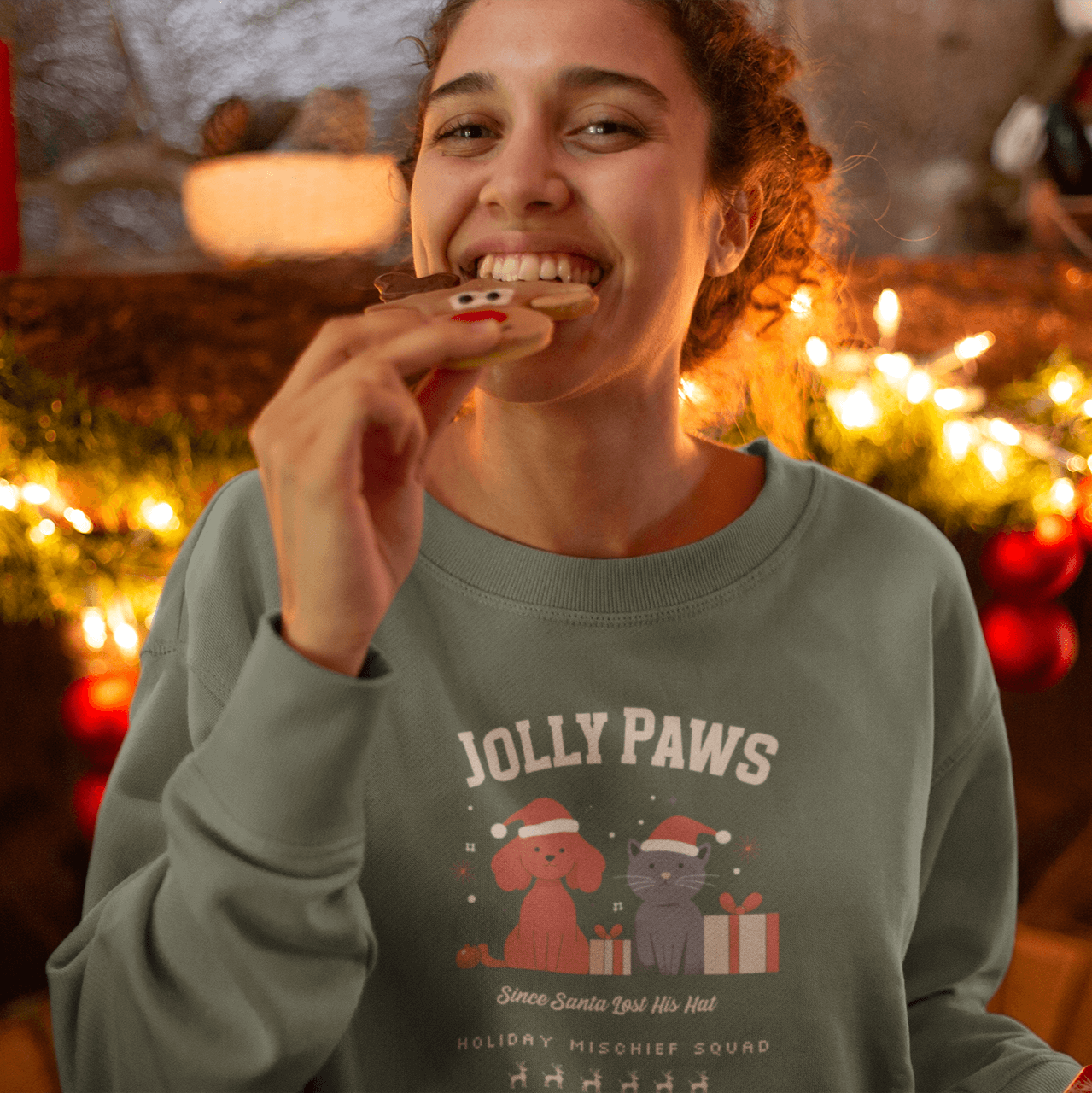 Young woman enjoying a cookie in a relaxed fit sweatshirt featuring dog and cat designs for Christmas.