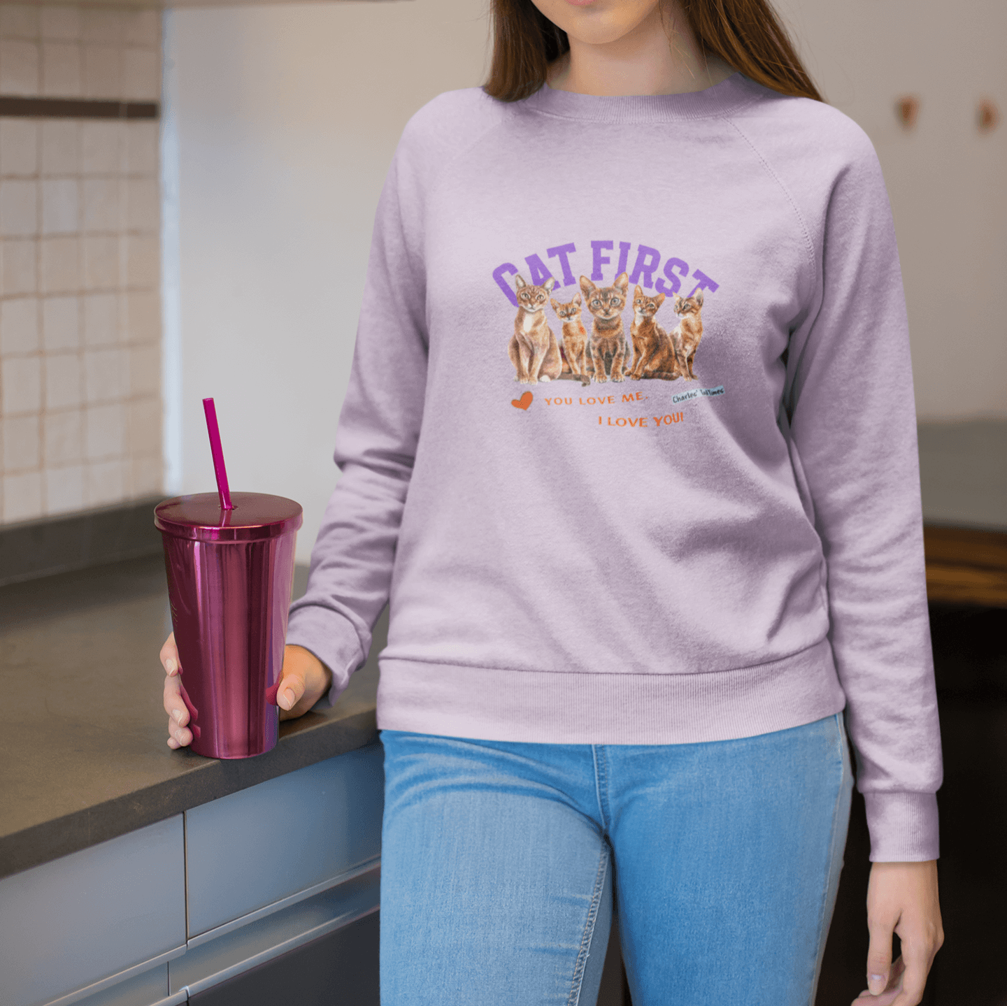 Woman wearing a lavender sweatshirt featuring Abyssinian cats and 