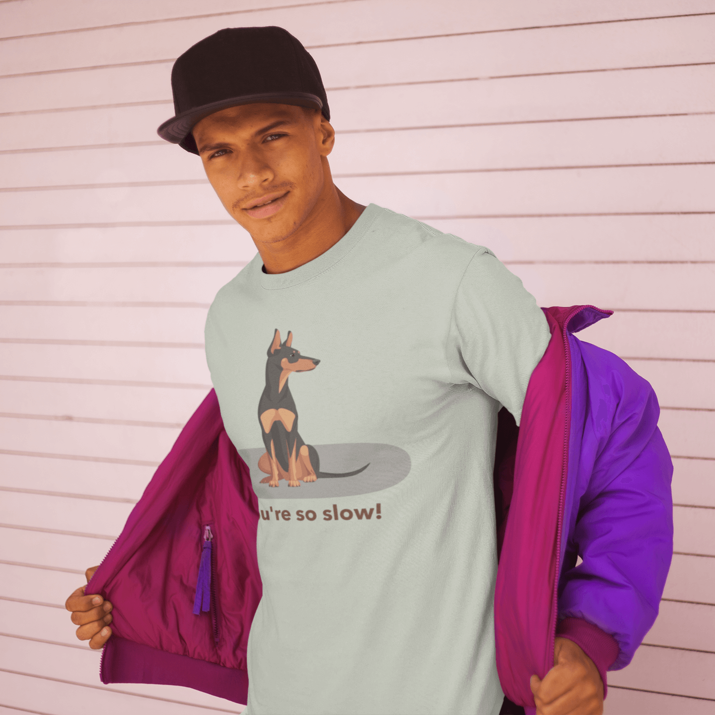 A man wearing a T-shirt featuring a cartoon Doberman illustration with the humorous text 