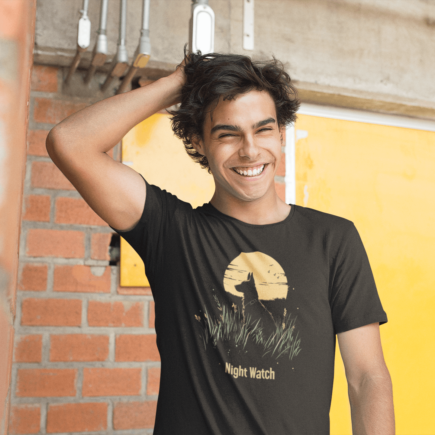 A young man wearing a T-shirt featuring the "Night Watch" design, which includes a dog sitting in tall grass with a bright moon in the background, creating a mysterious and vigilant vibe.