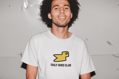 Model wearing Taily Bird Club white boxy t-shirt with yellow bird graphic, showcasing streetwear style and comfort.